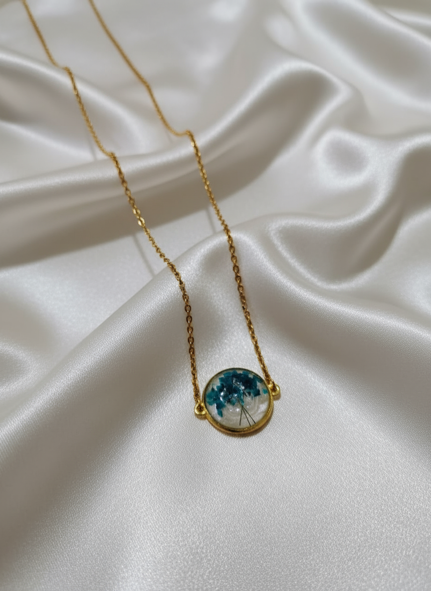 Blue floral resin necklace on off-white satin cloth