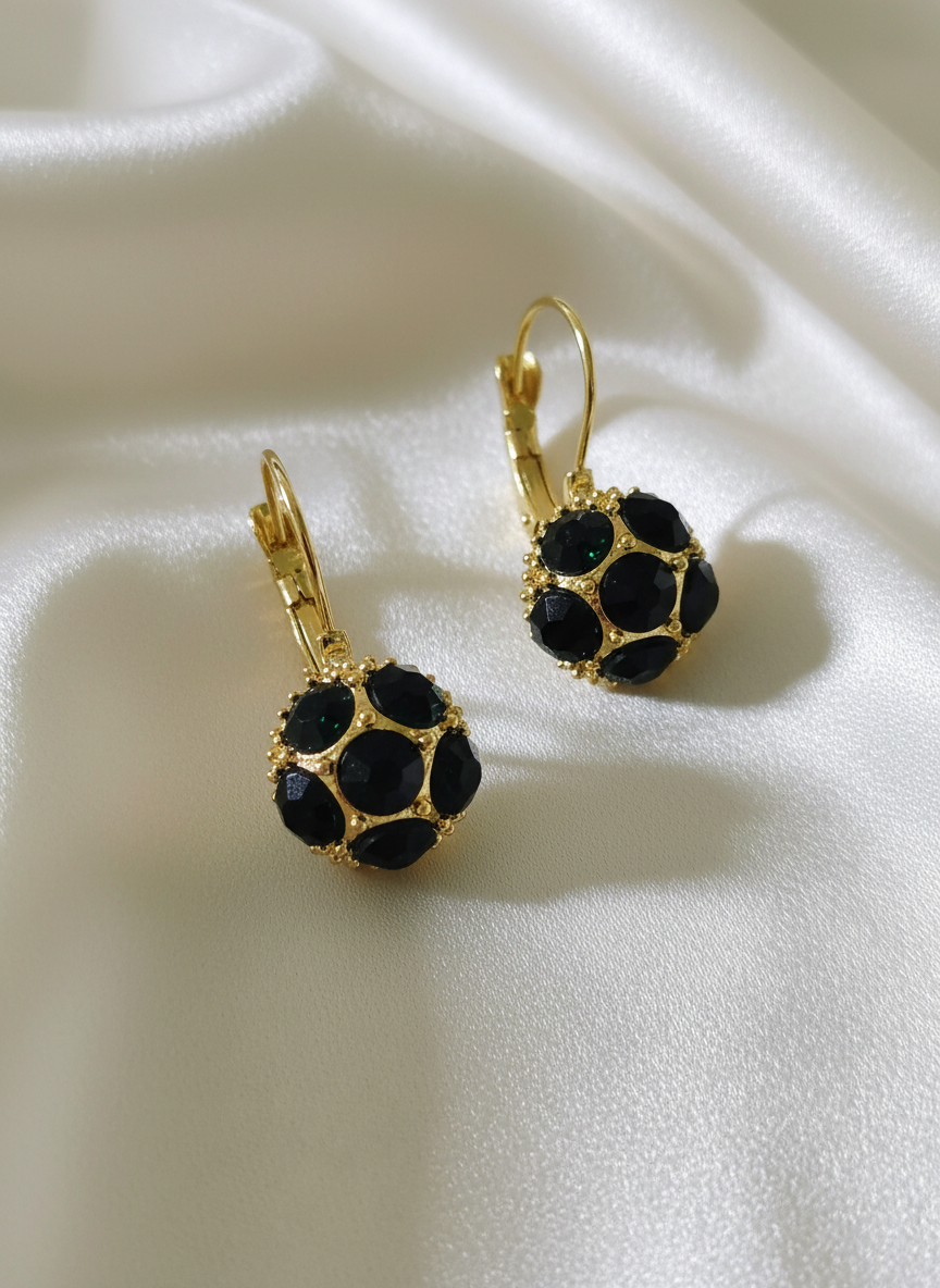 Elegant black gemstone earrings with gold settings on off-white satin cloth
