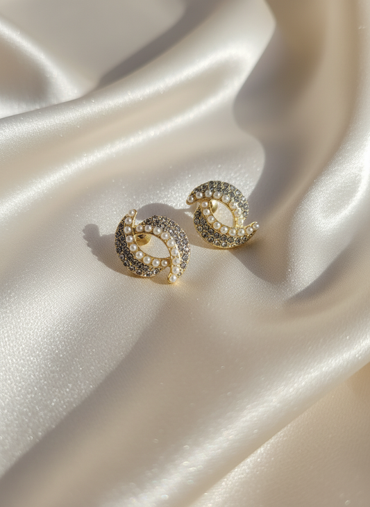 Elegant crystal-studded gold earrings displayed on light satin cloth
