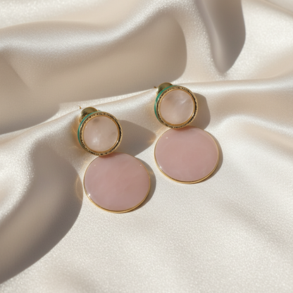 Elegant rose quartz and gold circle drop earrings displayed on luxurious satin cloth