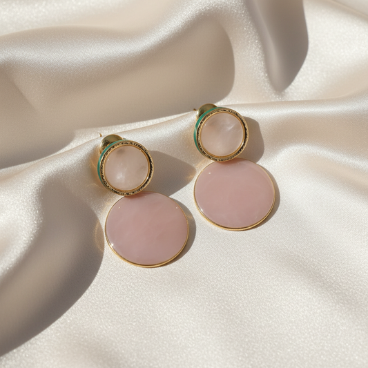 Elegant rose quartz and gold circle drop earrings displayed on luxurious satin cloth