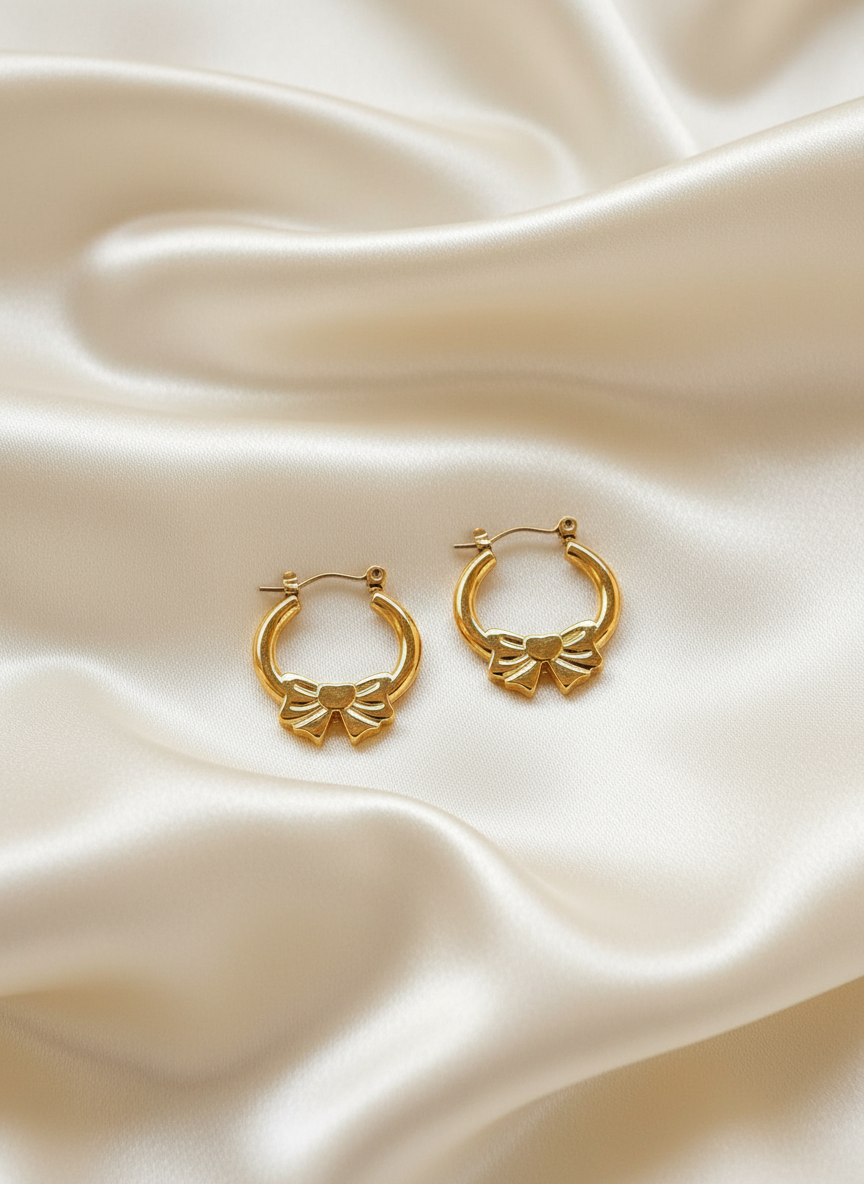 Gold bow hoop earrings on ivory satin