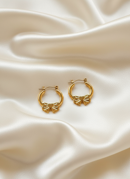 Gold bow hoop earrings on ivory satin