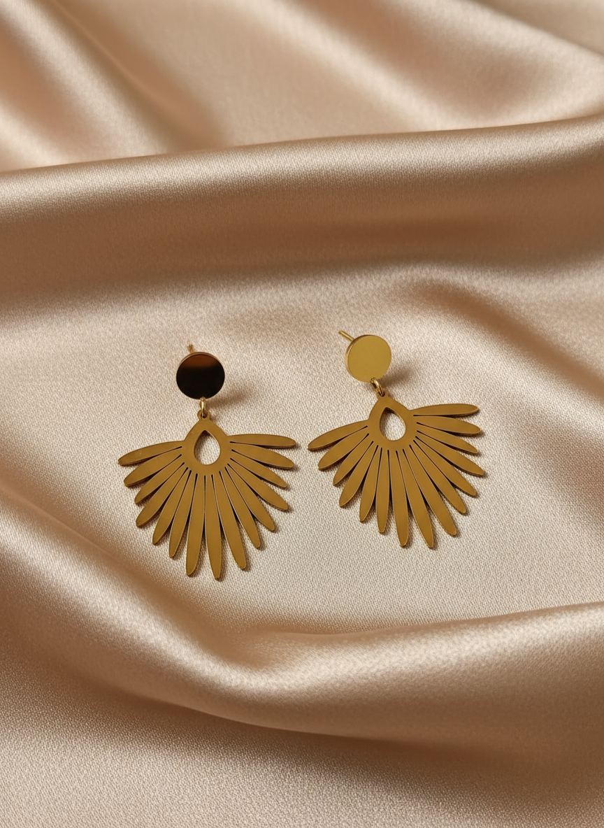 Gold feather earrings on light coffee satin cloth