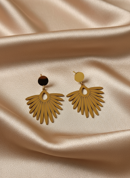 Gold feather earrings on light coffee satin cloth