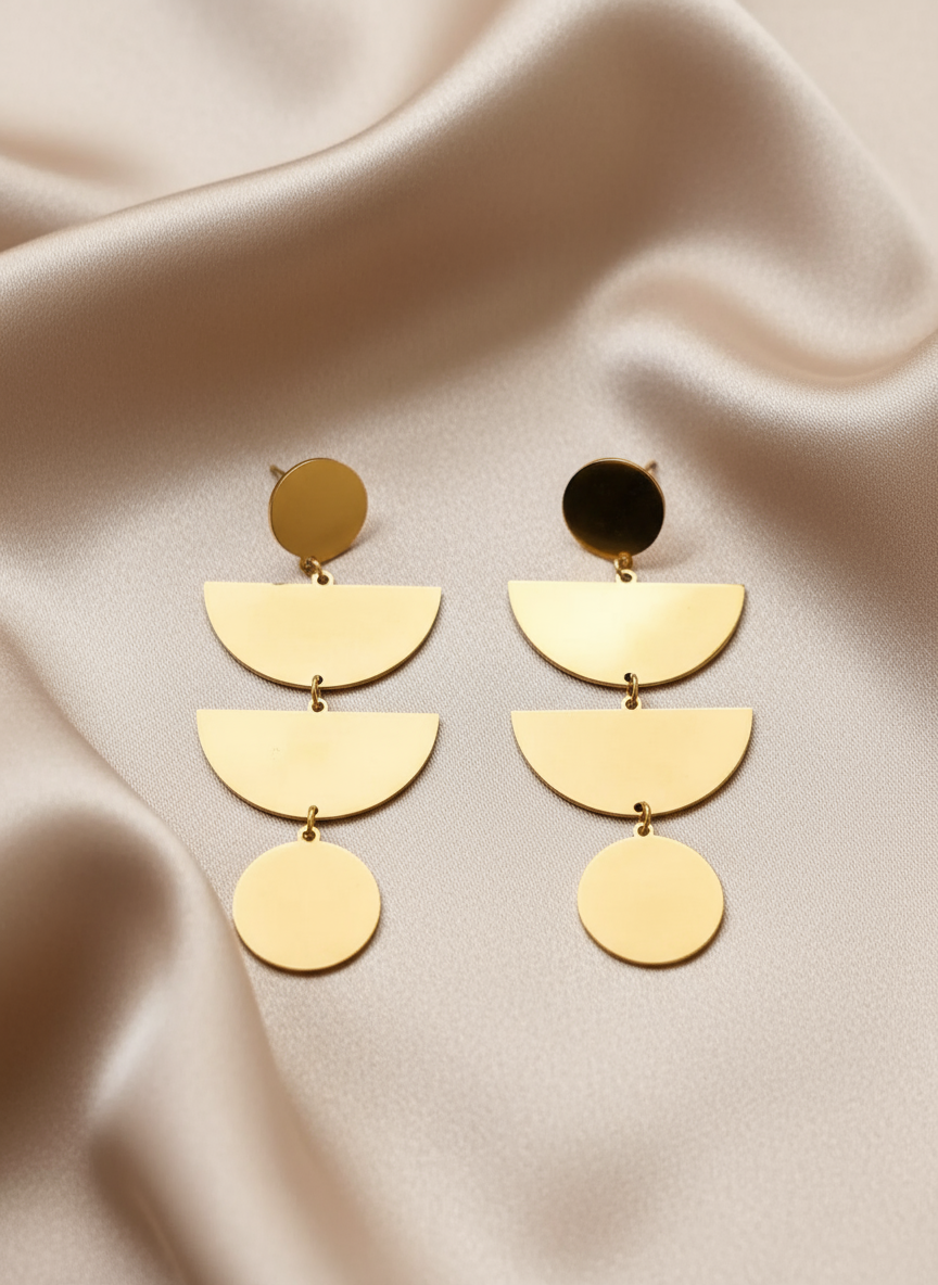 Gold geometric earrings on light coffee satin cloth
