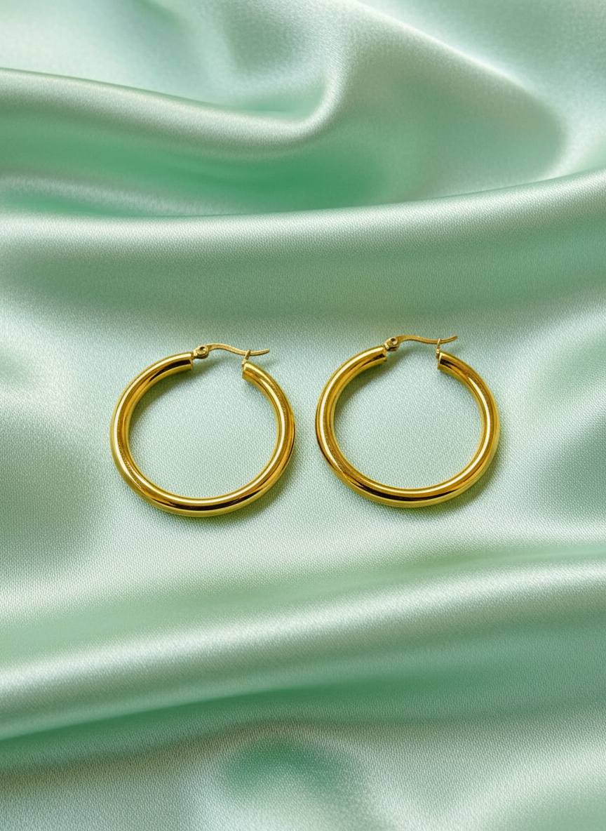 Gold hoop earrings on pista satin cloth