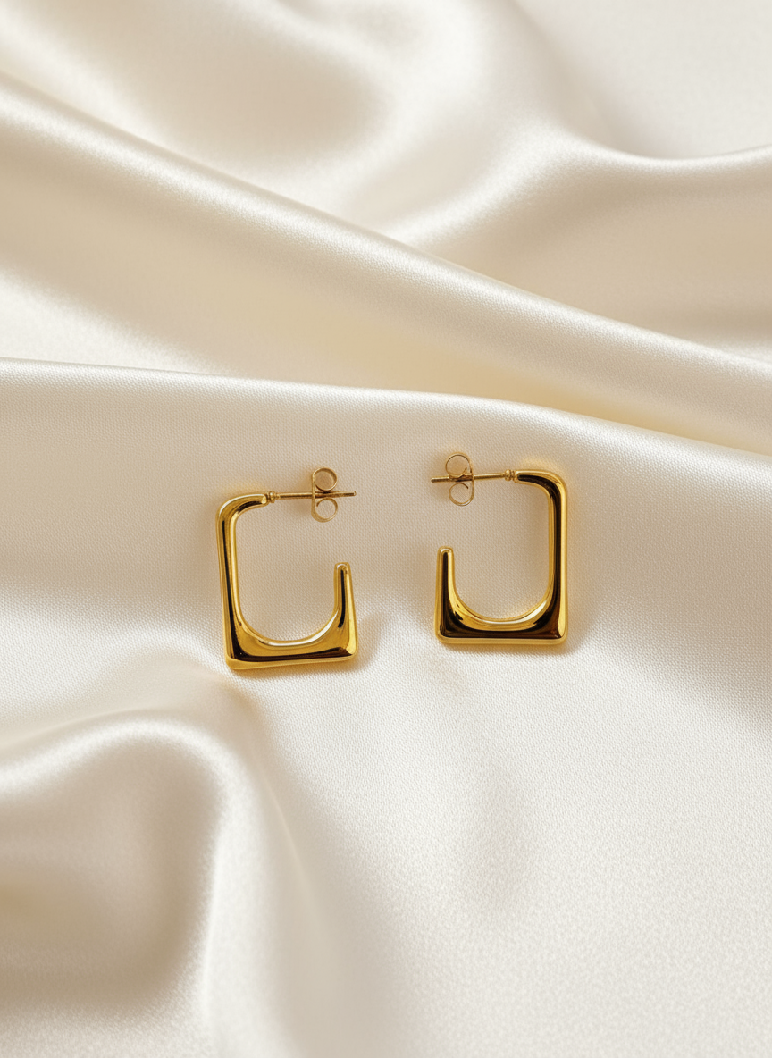 Gold square hoop earrings on ivory satin