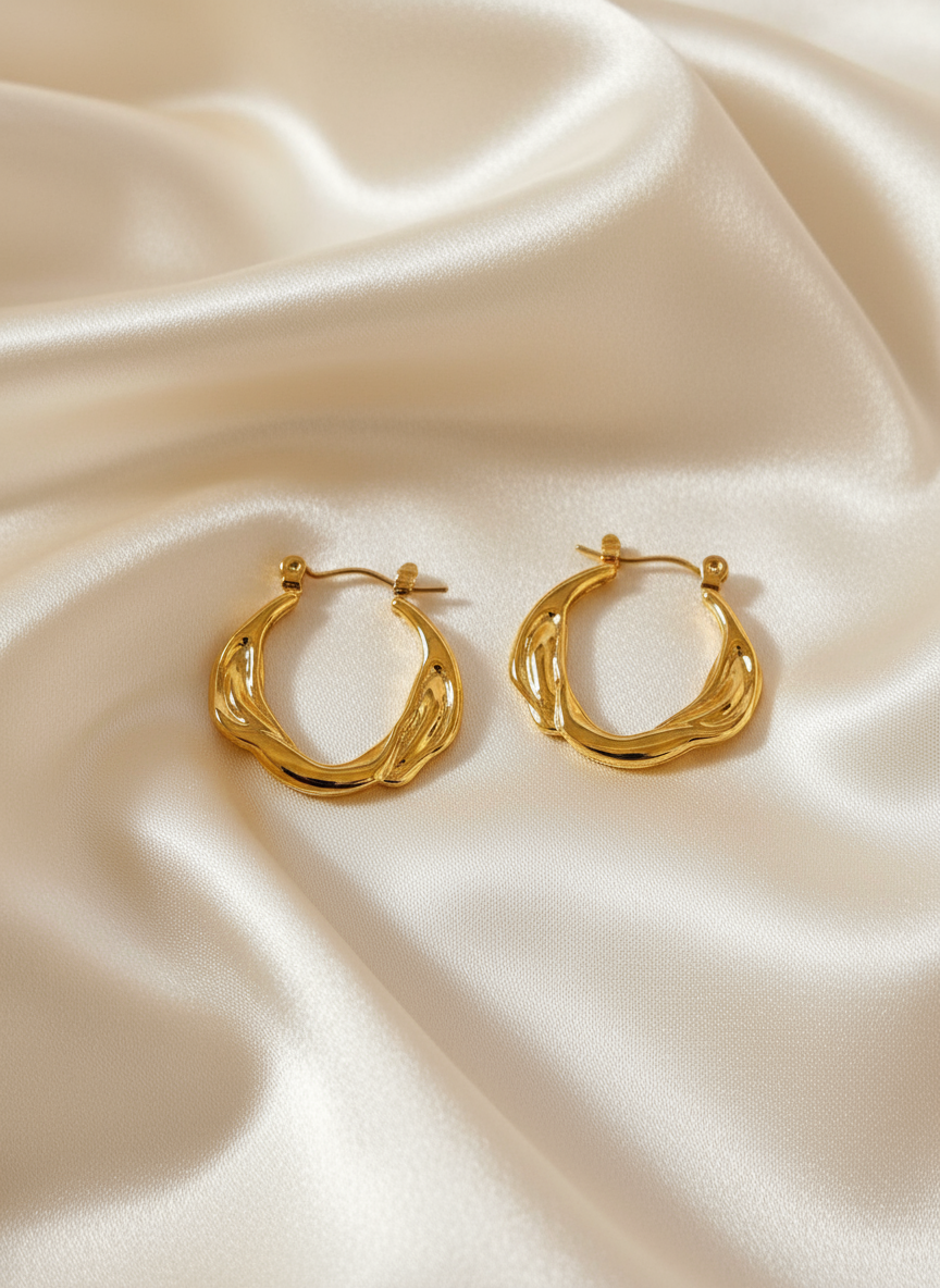 Gold twisted braided hoop earrings on ivory satin