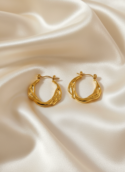 Gold twisted braided hoop earrings on ivory satin