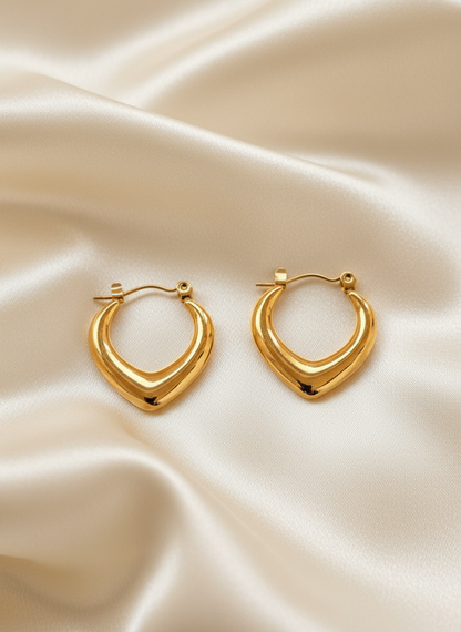 Gold V-shaped hoop earrings on ivory satin