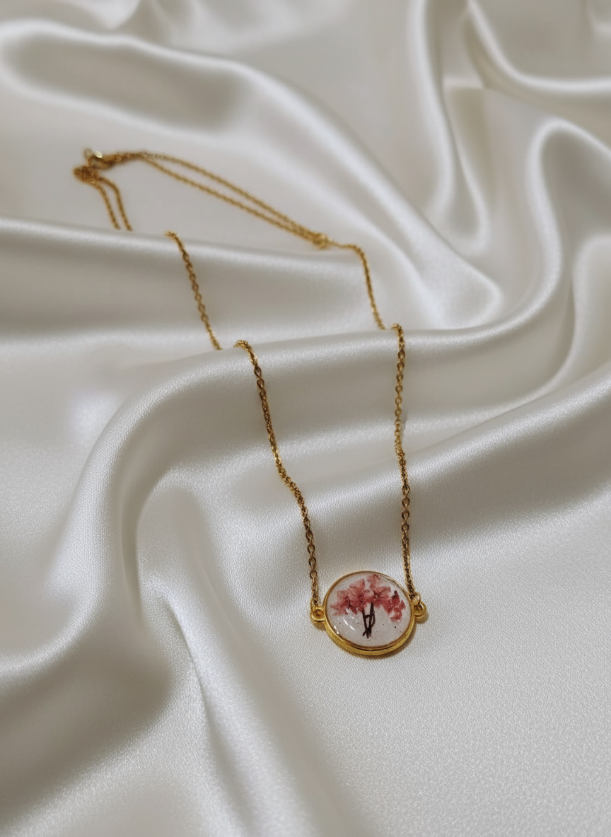 Pink floral resin necklace on off-white satin cloth